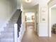 Hallway featuring a carpeted staircase, light wood floors, and an entryway into a kitchen at 9710 Iroquois Ct, Indianapolis, IN 46256