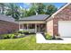 Charming brick home with lush landscaping leading to the inviting front porch, garden plants, and flower pots at 9735 Woodsong Ln, Indianapolis, IN 46229