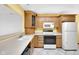 Well-lit kitchen with tiled floors, wood cabinets, and modern white appliances at 9735 Woodsong Ln, Indianapolis, IN 46229