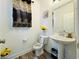 Cozy half bathroom with pedestal sink, decorative mirror, and warm accents offers convenience at 980 S Raylee Garden Dr, New Palestine, IN 46163