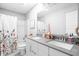 Bathroom with double sinks, white cabinets, gray quartz countertops, and a floral shower curtain at 10262 Rieslaner Cir, Zionsville, IN 46077