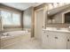 Bright bathroom featuring a large soaking tub, tiled floors, and a vanity with storage space at 1037 Deer Lake Dr, Carmel, IN 46032