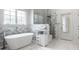 Bright bathroom featuring marble tiling, soaking tub, glass shower, and a storage cabinet at 1037 Deer Lake Dr, Carmel, IN 46032