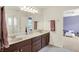 A well-lit bathroom featuring a double vanity and a view into an adjacent bedroom at 10587 Proposal Pointe Way, Fishers, IN 46040