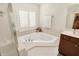 A bright bathroom corner featuring a soaking tub with shuttered windows and a tiled surround at 10587 Proposal Pointe Way, Fishers, IN 46040