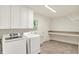 Well-lit laundry room features overhead cabinets, washer, dryer, utility sink, and folding table at 10587 Proposal Pointe Way, Fishers, IN 46040