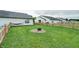 Large backyard featuring lush green grass, a fire pit, and a wooden fence at 1059 Wild Ivy Trl, Franklin, IN 46131