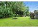 Spacious backyard with lush greenery, mature trees, shed, and a wooden deck with stairs at 1103 Rosengarten Dr, Greenwood, IN 46142