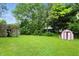 Spacious backyard featuring a wooden deck, mature trees, and a storage shed at 1103 Rosengarten Dr, Greenwood, IN 46142