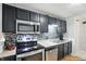 Galley kitchen featuring stainless appliances, stylish backsplash, and black cabinets at 1103 Rosengarten Dr, Greenwood, IN 46142