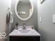 Bright half-bathroom featuring a round mirror and a modern sink with black cabinets at 12584 Cold Stream Rd, Noblesville, IN 46060