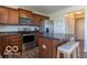 Well-lit kitchen with stainless steel appliances, dark countertops and warm wood cabinets at 12584 Cold Stream Rd, Noblesville, IN 46060