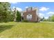 Brick home's backyard with lush green lawn and landscaping, surrounded by mature trees at 13624 Alston Dr, Fishers, IN 46037