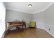 Well-lit living room with wood floors featuring piano and upholstered chair at 13624 Alston Dr, Fishers, IN 46037
