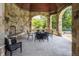 Outdoor dining area featuring a stone fireplace and views of the landscaped backyard at 18 Lost Run Ln, Zionsville, IN 46077