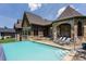 Back of the house featuring infinity pool with stone patio, outdoor living, and beautiful architecture at 18 Lost Run Ln, Zionsville, IN 46077