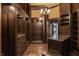 Expansive walk-in closet features hardwood floors, custom shelving and cabinetry, and stunning chandelier at 18 Lost Run Ln, Zionsville, IN 46077