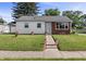 Charming single-story home with a well-manicured lawn and American flags lining the sidewalk leading to the front door at 206 Allen Ln, Greenfield, IN 46140