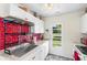 Well-lit kitchen showcasing a stainless steel sink, white cabinets, and bright red tile backsplash at 206 Allen Ln, Greenfield, IN 46140