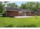 Well-manicured backyard showcasing the patio area, mature trees, and brick home exterior at 220 E Tilden Dr, Brownsburg, IN 46112