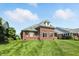 Manicured backyard with brick house, well-maintained lawn, and beautiful landscaping under a clear sky at 2251 Somerset Dr, Franklin, IN 46131