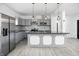 Modern kitchen with stainless steel appliances, sleek gray cabinets, a large island with a dark countertop and pendant lighting at 3210 Hovey St, Indianapolis, IN 46218