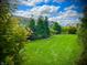A beautifully landscaped backyard with green lawn, trees, and view of the neighborhood homes on a sunny day at 4281 Viewforth Ln, Bargersville, IN 46106
