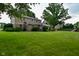 Lush backyard with mature trees, a well-kept lawn, and a partial view of the home's exterior and outdoor play area at 4585 Abbey Dr, Carmel, IN 46033