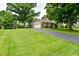 Suburban home with long driveway, basketball hoop, large lawn, and mature trees in the yard at 4585 Abbey Dr, Carmel, IN 46033