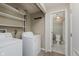 Functional laundry room with washer, dryer, and shelving; bathroom with elegant wallpaper viewable through doorway at 49 Druid Hill Ct # 0, Carmel, IN 46032