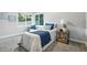 Bright bedroom features a twin bed with white bedding and blue accents, side table with décor, and a chair by the window at 5170 Mt Pleasant N St, Greenwood, IN 46142
