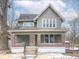 Charming two-story home featuring a covered front porch, red brick accents and green painted siding at 5511 E University Ave, Indianapolis, IN 46219