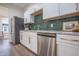 Modern kitchen features white cabinets, emerald subway tile backsplash, stainless appliances, and gold hardware at 5511 E University Ave, Indianapolis, IN 46219