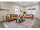 Bright living room with two leather sofas, neutral walls, and a modern coffee table on stylish carpet at 5511 E University Ave, Indianapolis, IN 46219