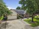 Brick house featuring an attached garage and concrete driveway surrounded by mature trees and landscaping at 5591 Royal Troon Way, Avon, IN 46123