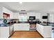 Bright kitchen features white cabinetry, stainless steel appliances, and hardwood floors at 621 S Jefferson St, Brownsburg, IN 46112