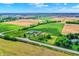 An aerial view showcasing a farm house, barn, in a country setting surrounded by lush green fields and mature trees at 7165 W State Road 252 W Rd, Edinburgh, IN 46124