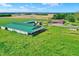 An aerial view featuring a spacious barn and a house with a pool, surrounded by lush green fields and mature trees at 7165 W State Road 252 W Rd, Edinburgh, IN 46124