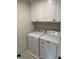 Well-lit laundry room with a white washer and dryer set and overhead storage cabinets for convenience at 7270 W Stone Pass, New Palestine, IN 46163