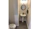 Compact powder room features a modern pedestal sink, round mirror, and stylish gray flooring at 7270 W Stone Pass, New Palestine, IN 46163