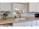 Well-lit kitchen sink with white cabinets, neutral countertops, and an open view to the dining area at 741 Chestnut Ln, Brownsburg, IN 46112