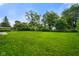 View of a spacious, well-manicured backyard with mature trees and lush green grass at 8025 Meadow Ln, Indianapolis, IN 46227