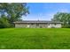 Backyard with large grass area, trees, and a house with grey siding at 8025 Meadow Ln, Indianapolis, IN 46227