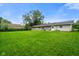 Large, green backyard with trees and a grey-sided house at 8025 Meadow Ln, Indianapolis, IN 46227