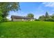 Backyard with large grassy area, trees, and grey sided house in the background at 8025 Meadow Ln, Indianapolis, IN 46227