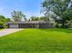 Charming single-story home featuring a lush green lawn, attached garage, and a welcoming front porch at 8025 Meadow Ln, Indianapolis, IN 46227