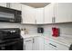 Bright kitchen featuring black appliances, white cabinets, and white marble-style countertop at 8025 Meadow Ln, Indianapolis, IN 46227