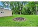 Backyard with lush green grass, mature trees, and a charming fire pit surrounded by rocks at 8760 Big Bend Rd, Martinsville, IN 46151