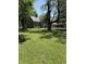 Spacious front yard showcases a classic home nestled among mature trees, providing a picturesque and tranquil setting at 9168 S State Road 9, Flat Rock, IN 47234