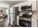 Modern kitchen features stainless steel appliances and white cabinets, open to living room at 946 N Temple Ave, Indianapolis, IN 46201